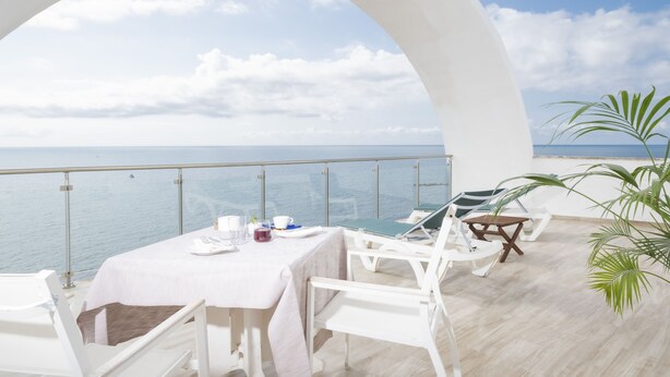 Una terraza con una mesa para dos, con vista al mar.