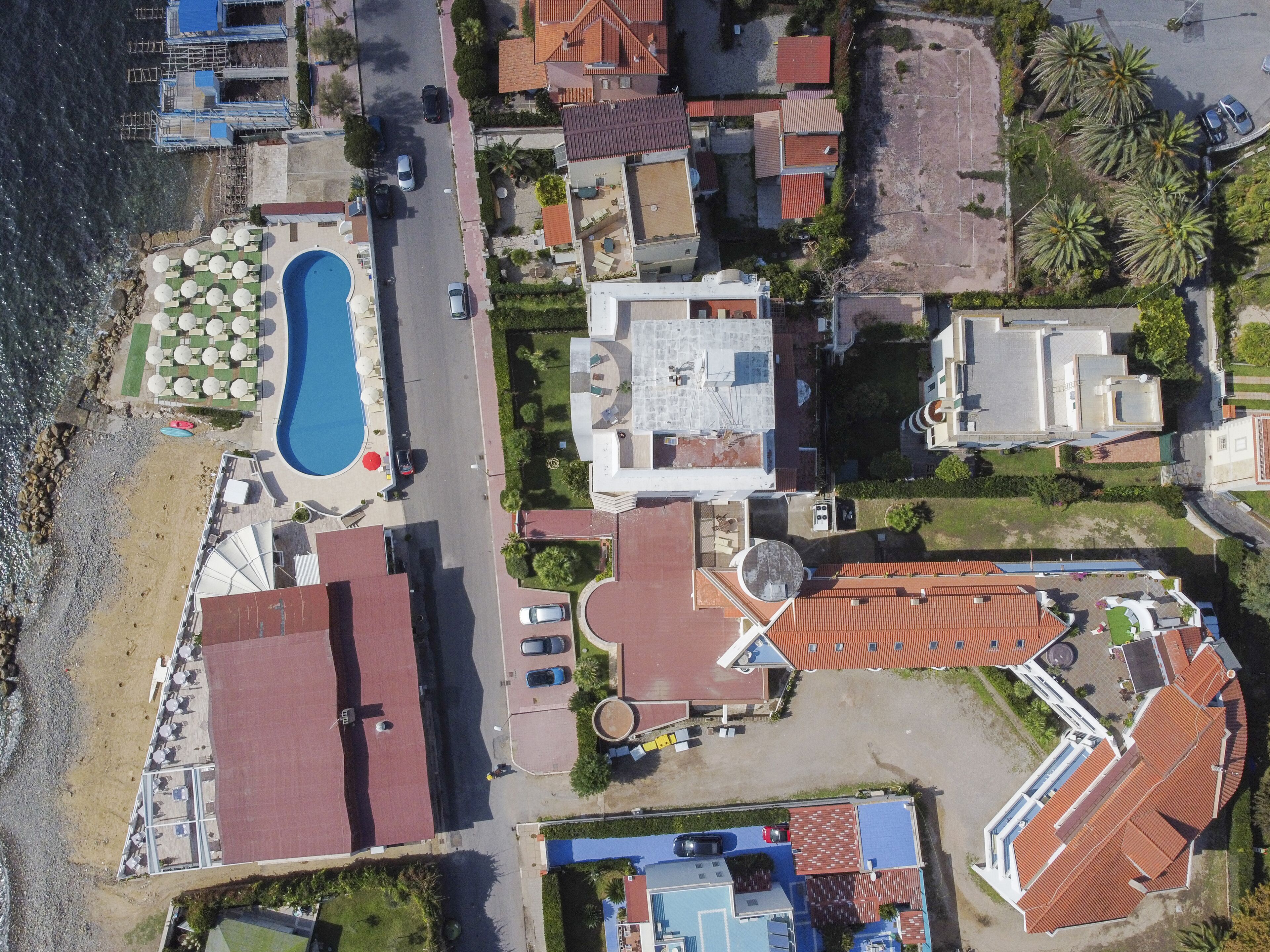 Vista aérea de un hotel costero con piscina, varias construcciones y una zona de playa.