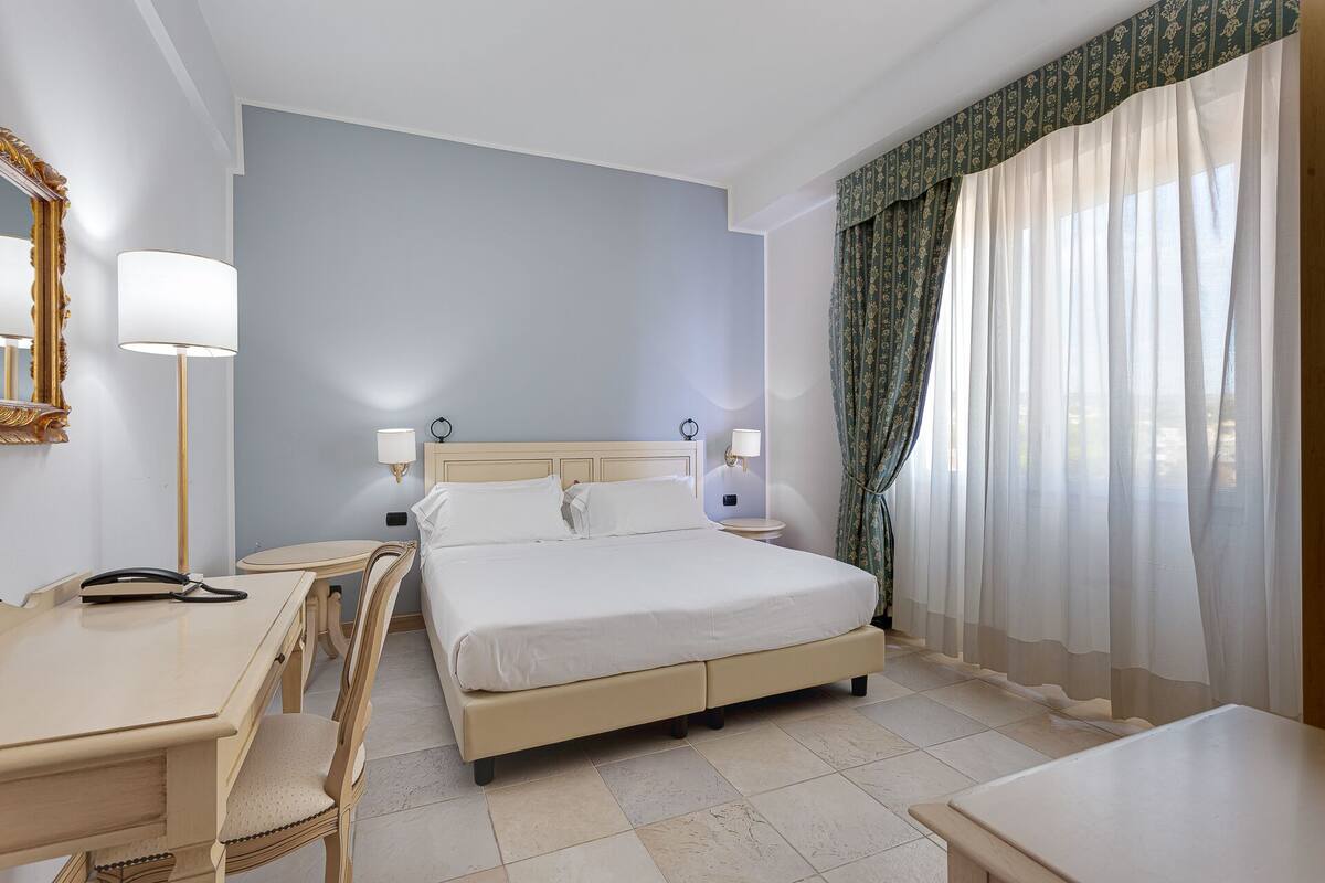 Una habitación de hotel con cama, mesitas de noche, un escritorio y una silla.