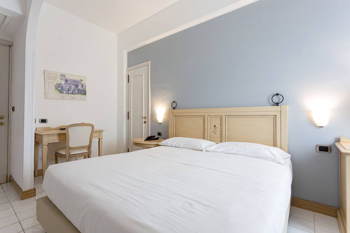 Una habitación de hotel con una cama grande, un escritorio, una silla y una mesita.
