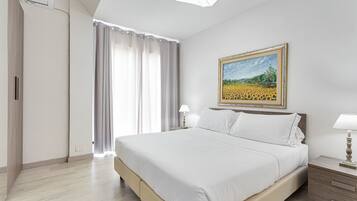 A hotel room with a bed, a nightstand, a lamp, a painting, and a window with curtains.