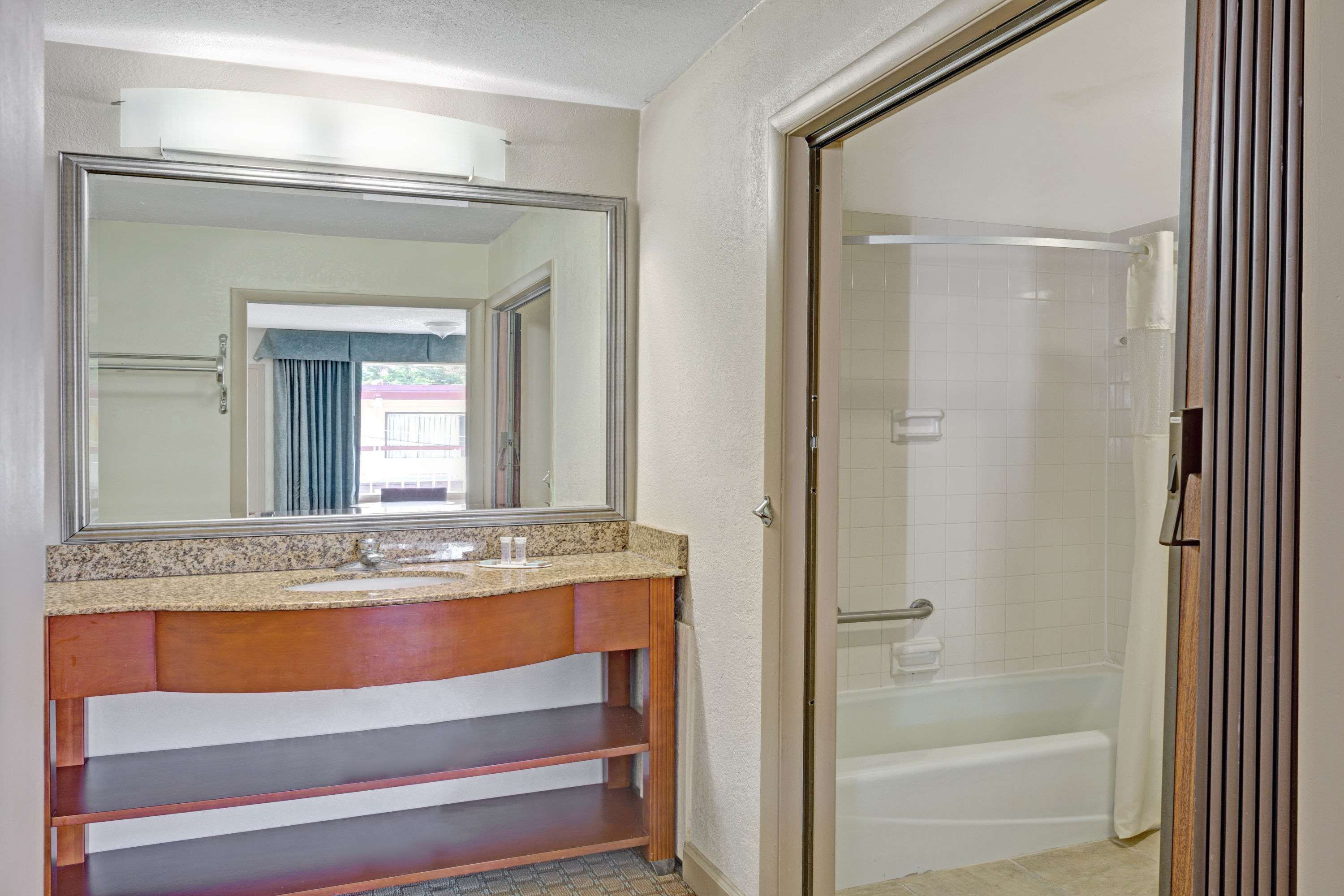 Un baño con un espejo grande, un lavabo, tocador y zona de ducha.