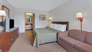 Une chambre d’hôtel avec un lit, un canapé, un téléviseur posé sur une commode et un miroir.
