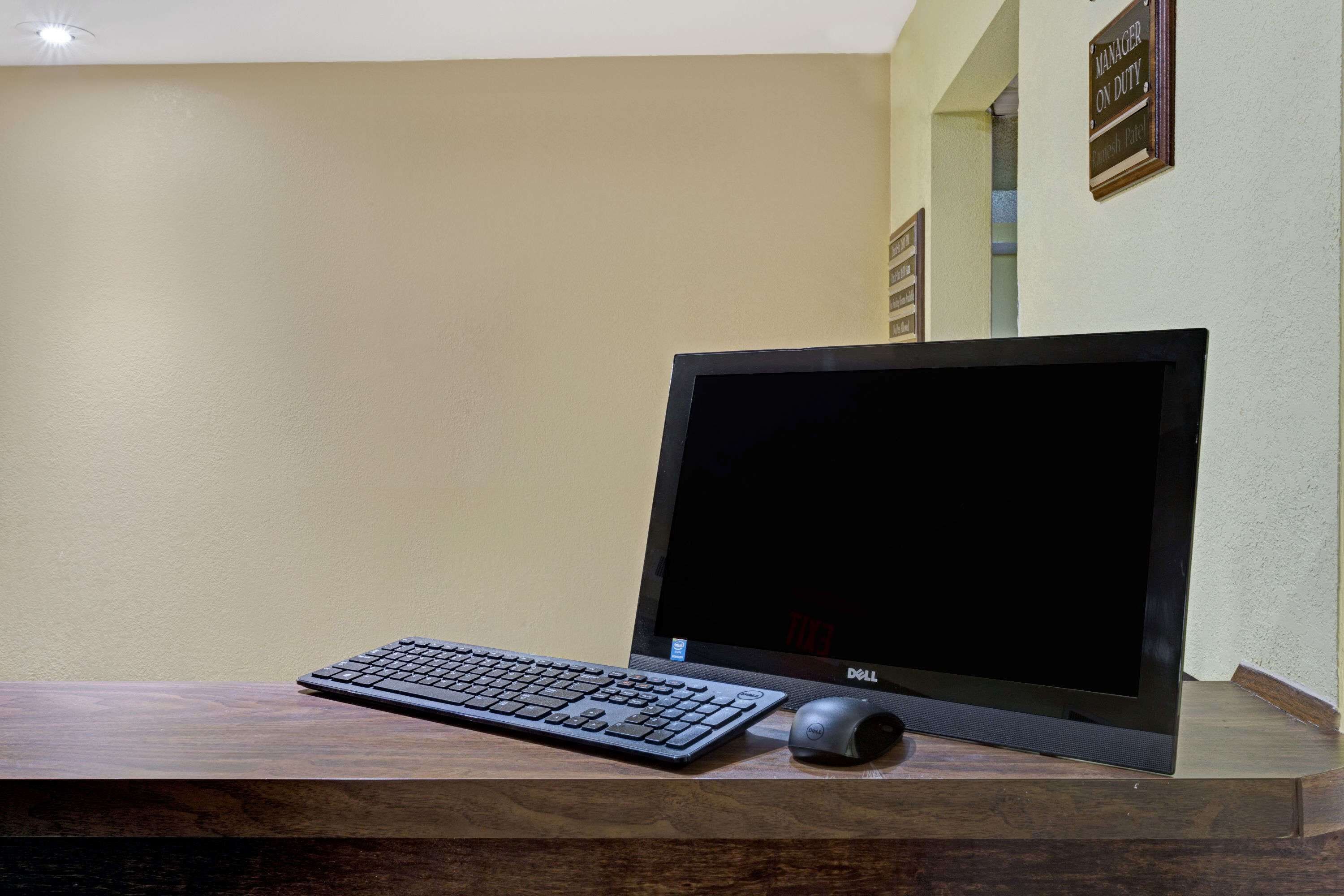 A desk with a computer monitor, keyboard, and mouse.