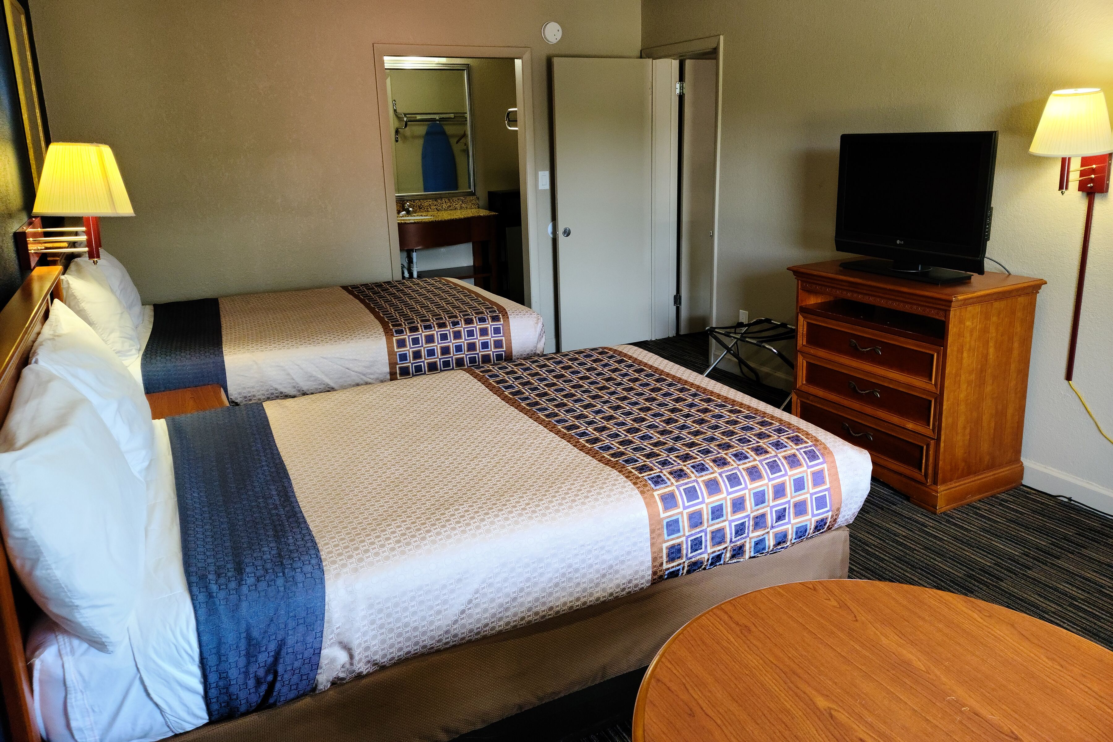 Habitación de hotel con dos camas, televisor, escritorio y una silla.