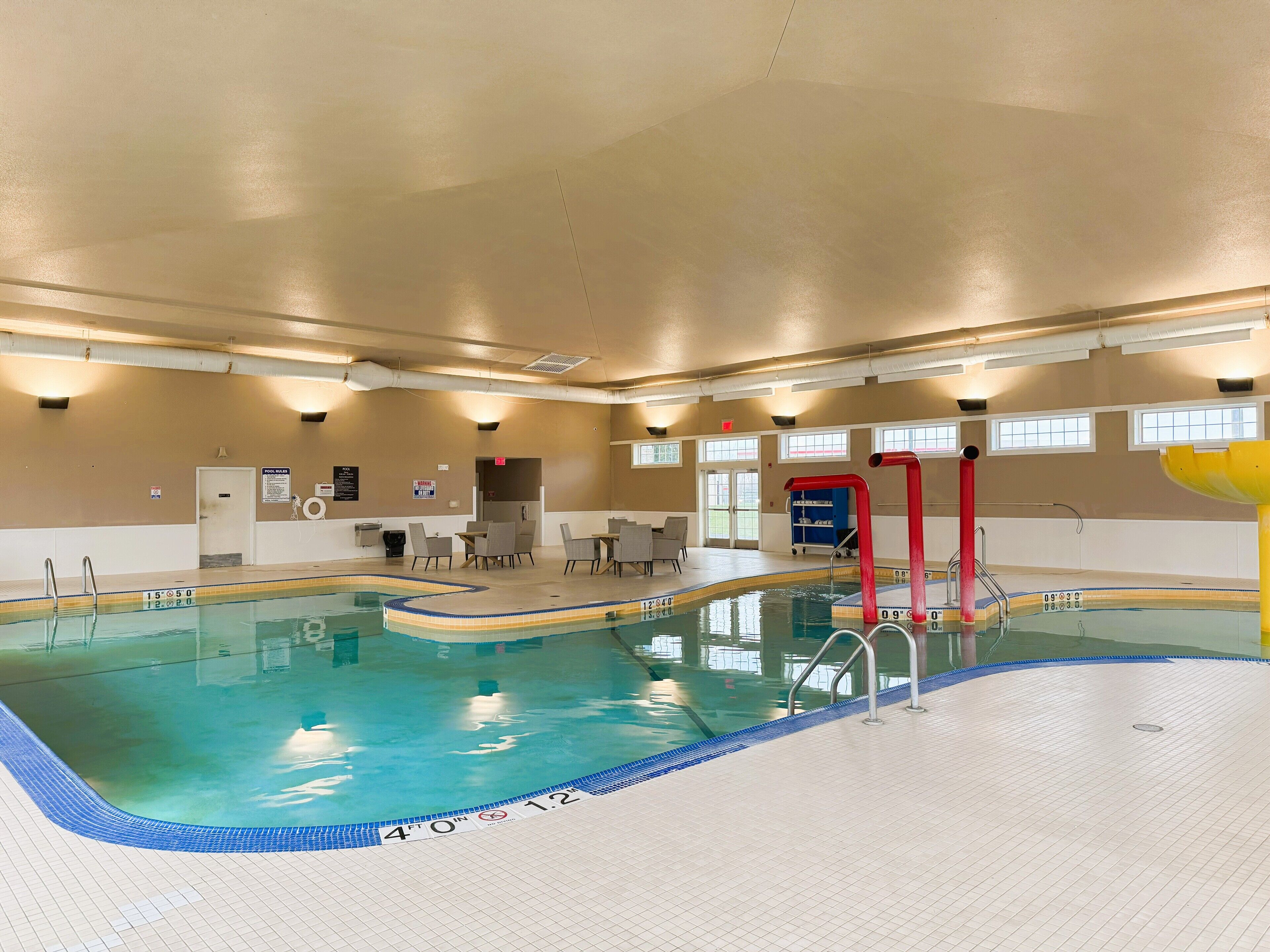 Una piscina interna profonda 12 metri, con spogliatoio e area relax con tavoli e sedie.