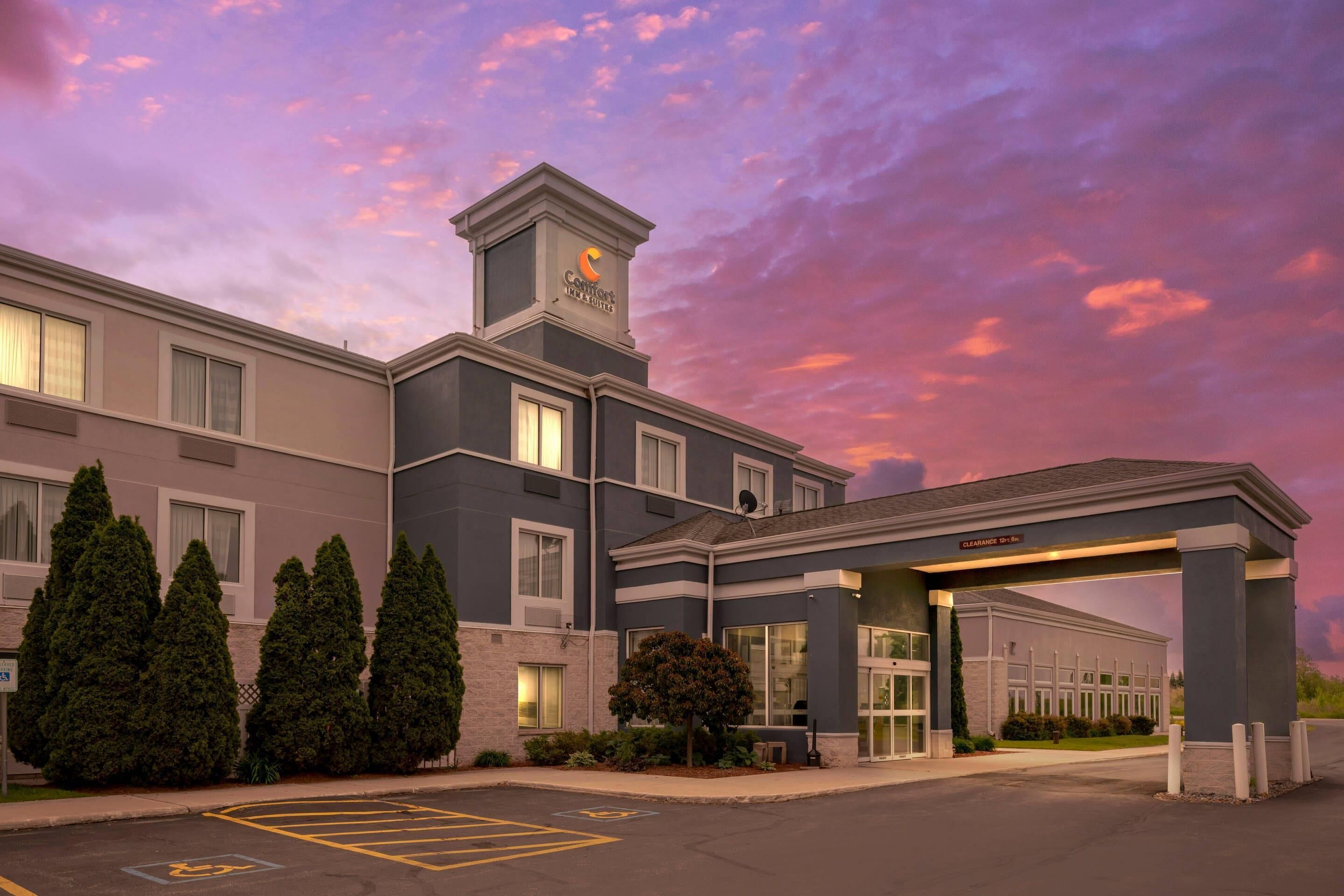 A hotel with a modern design, featuring a covered entrance and a parking lot with handicapped spaces.