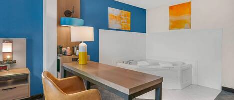 A hotel room with a wooden desk, a brown leather chair, a white bathtub, and a blue accent wall.