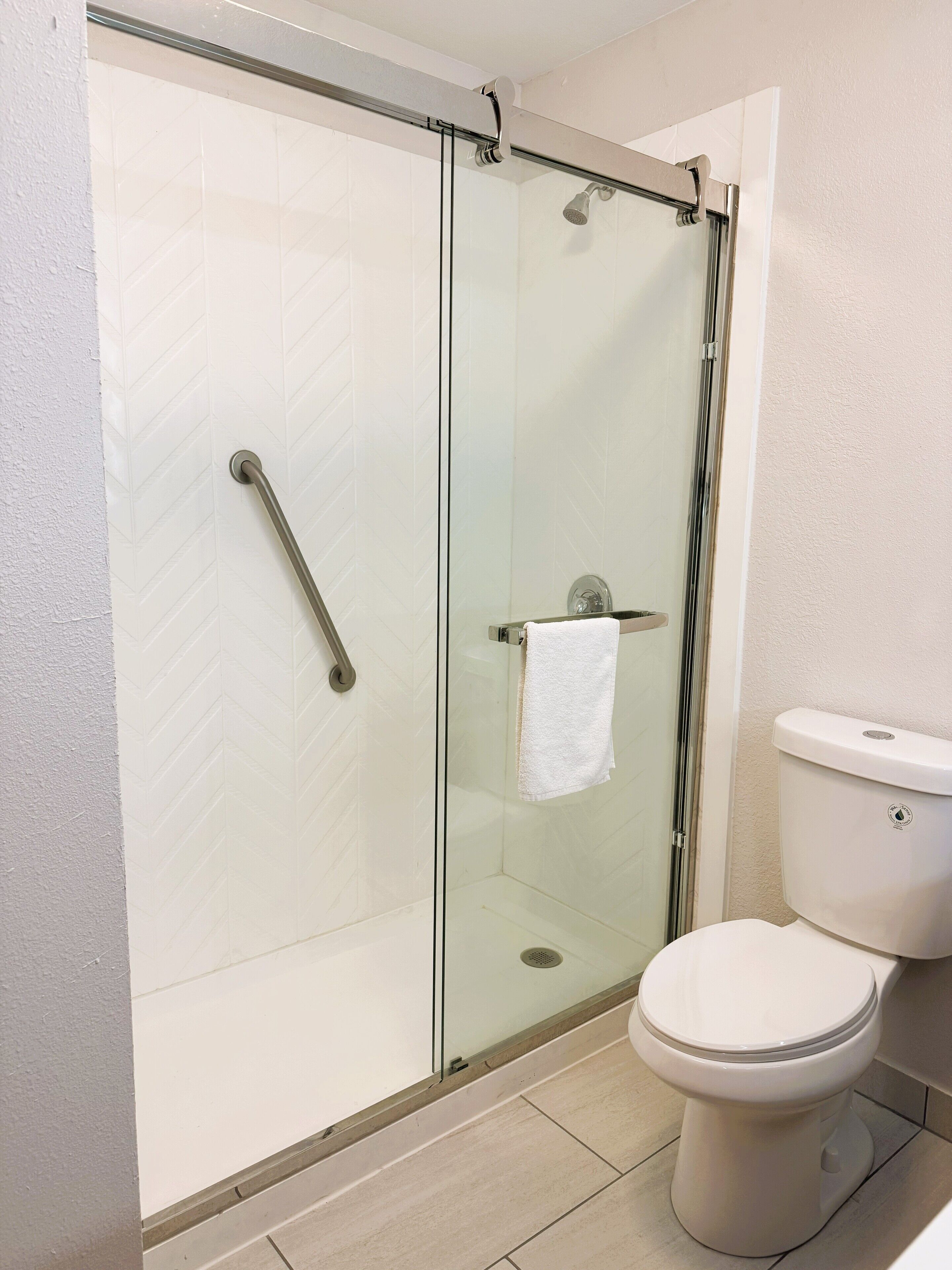 A bathroom with a glass-enclosed shower, a white toilet, and a towel rack.