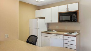 A compact kitchen with white cabinets, a microwave, a refrigerator, and a dishwasher.