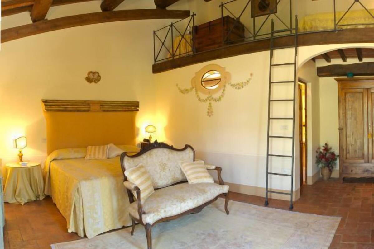 Un dormitorio con cama, sofá, escalera y puerta de madera.
