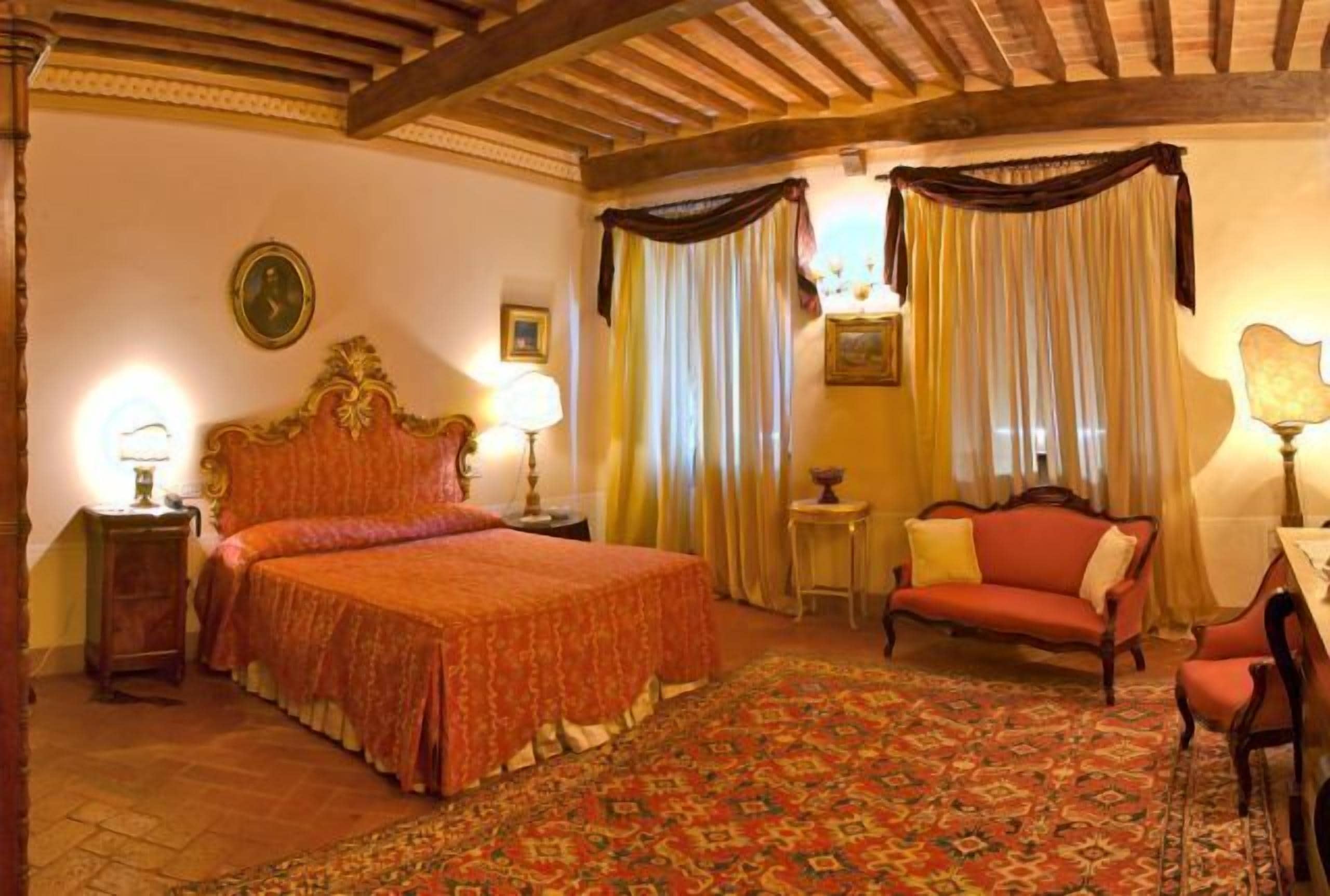 A traditional bedroom with a large bed, a sofa, a small table, and a lamp.
