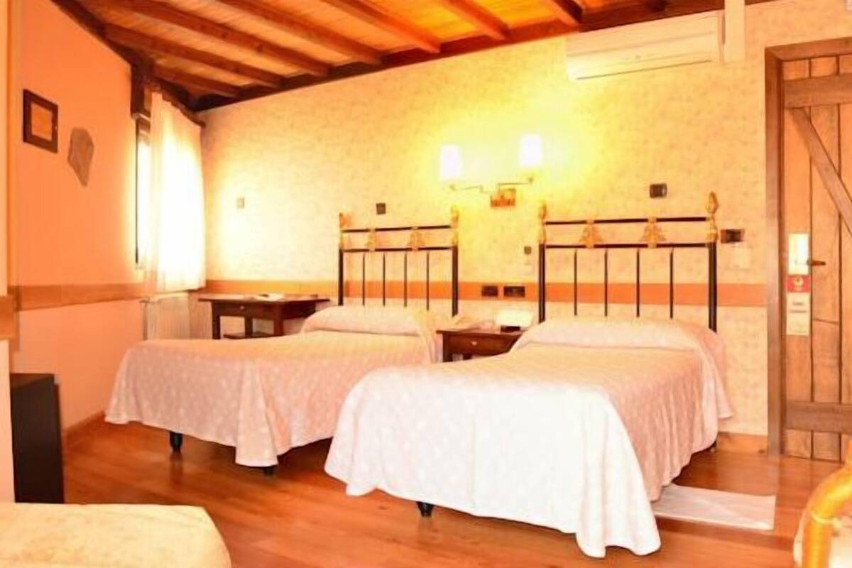 Una habitación con dos camas, una puerta de madera y una silla.