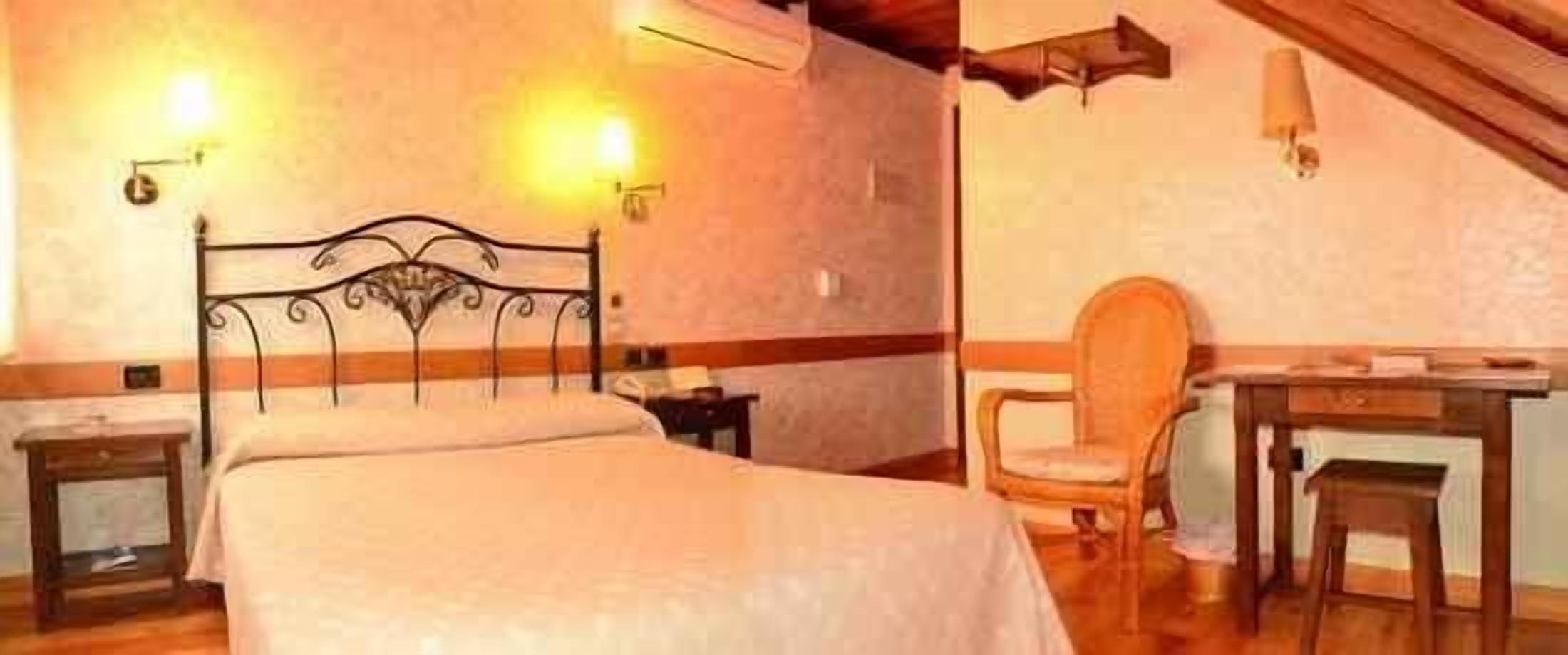 Un dormitorio con cama, mesitas de noche, una silla y un escritorio.