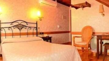 Un dormitorio con cama, mesitas de noche, una silla y un escritorio.