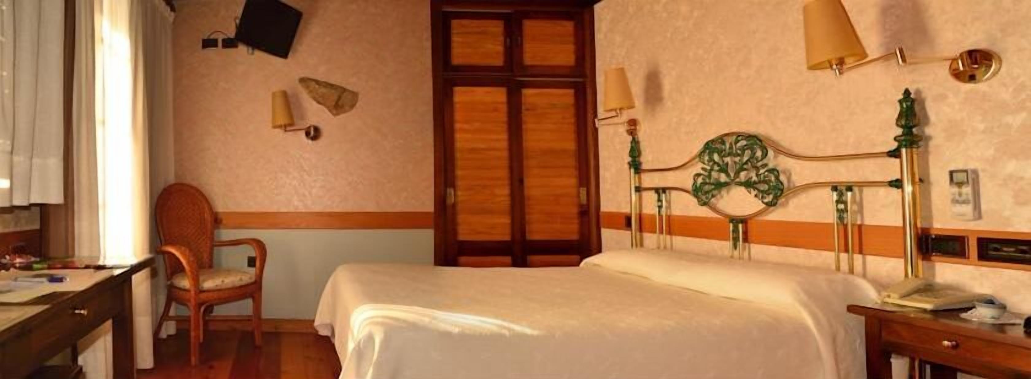 Una habitación de hotel con cama, escritorio, silla, lámpara y puerta.