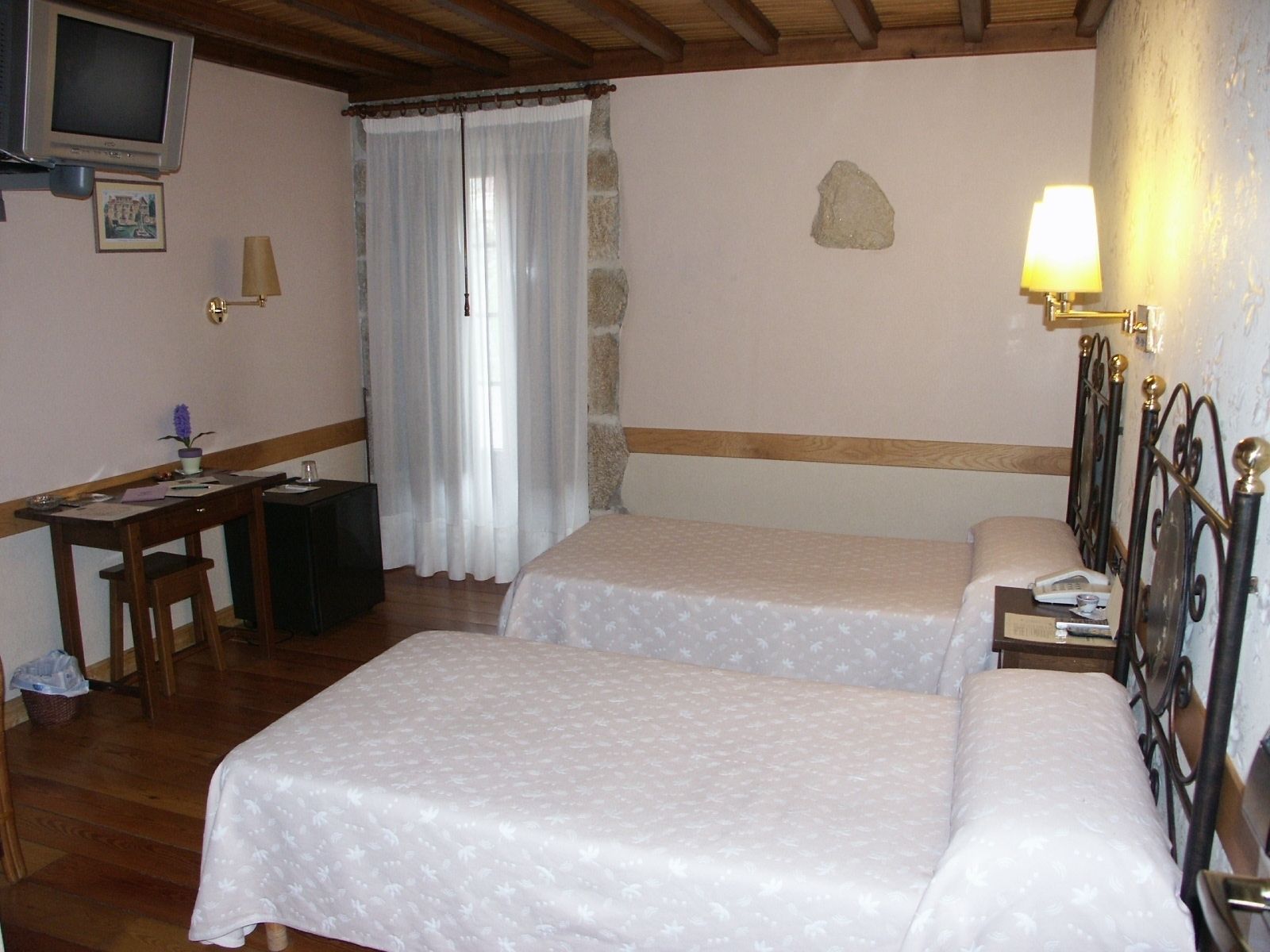 Un dormitorio con dos camas, un escritorio, una silla, un televisor y una lámpara.