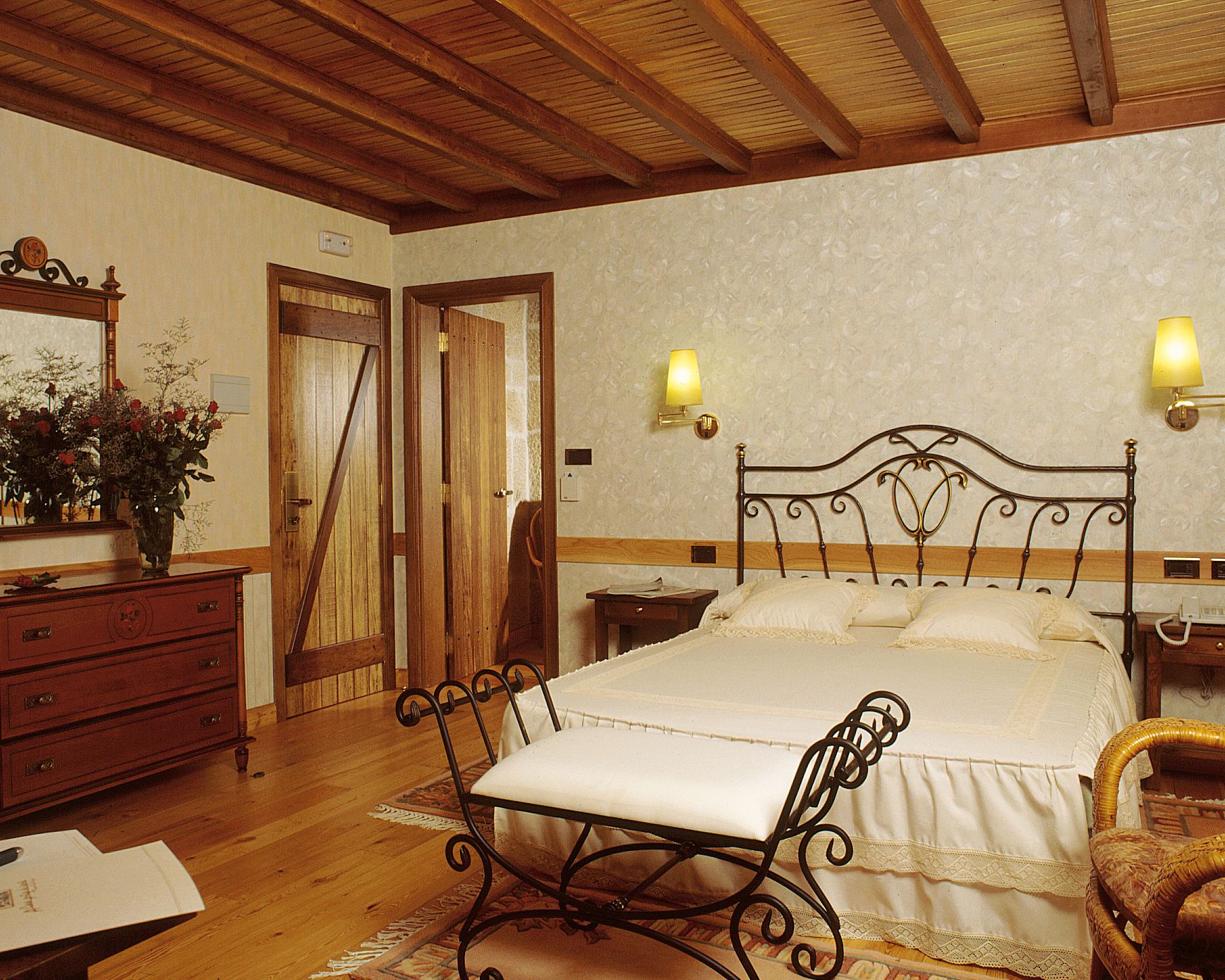 Un dormitorio con cabecera de cama de madera, una mesita de noche, un aparador y un espejo.