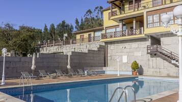 Una piscina con sillas de descanso y un muro de piedra.