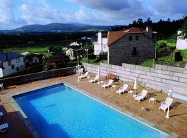 Una piscina con tumbonas y un edificio de piedra al fondo.