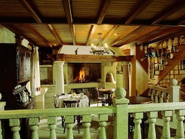 Un interior rústico con chimenea de piedra, vigas de madera y una escalera.