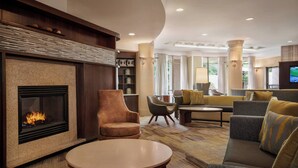 A modern hotel lobby with a fireplace, comfortable seating, and a television. - Courtyard by Marriott Middletown Goshen (Middletown)