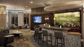 A modern bar area with a curved counter, bar stools, and a television screen. - Courtyard by Marriott Middletown Goshen (Middletown)