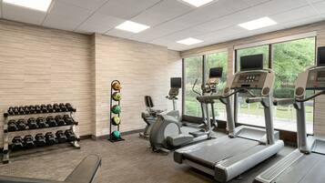 A gym with treadmills, elliptical machines, and a rack of dumbbells.