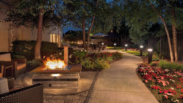 A landscaped outdoor area with a fire feature, seating, and a pathway. - Courtyard by Marriott Middletown Goshen (Middletown)