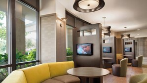 A modern hotel lobby with a seating area, large windows, and a television screen. - Courtyard by Marriott Middletown Goshen (Middletown)