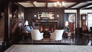 A cozy living room with a fireplace, wooden beams, and comfortable seating. - Black Point Inn (Scarborough)