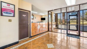 A hotel reception area with a tiled floor, a reception desk, and a glass door leading outside. - Econo Lodge  Inn & Suites Macon West (Macon)