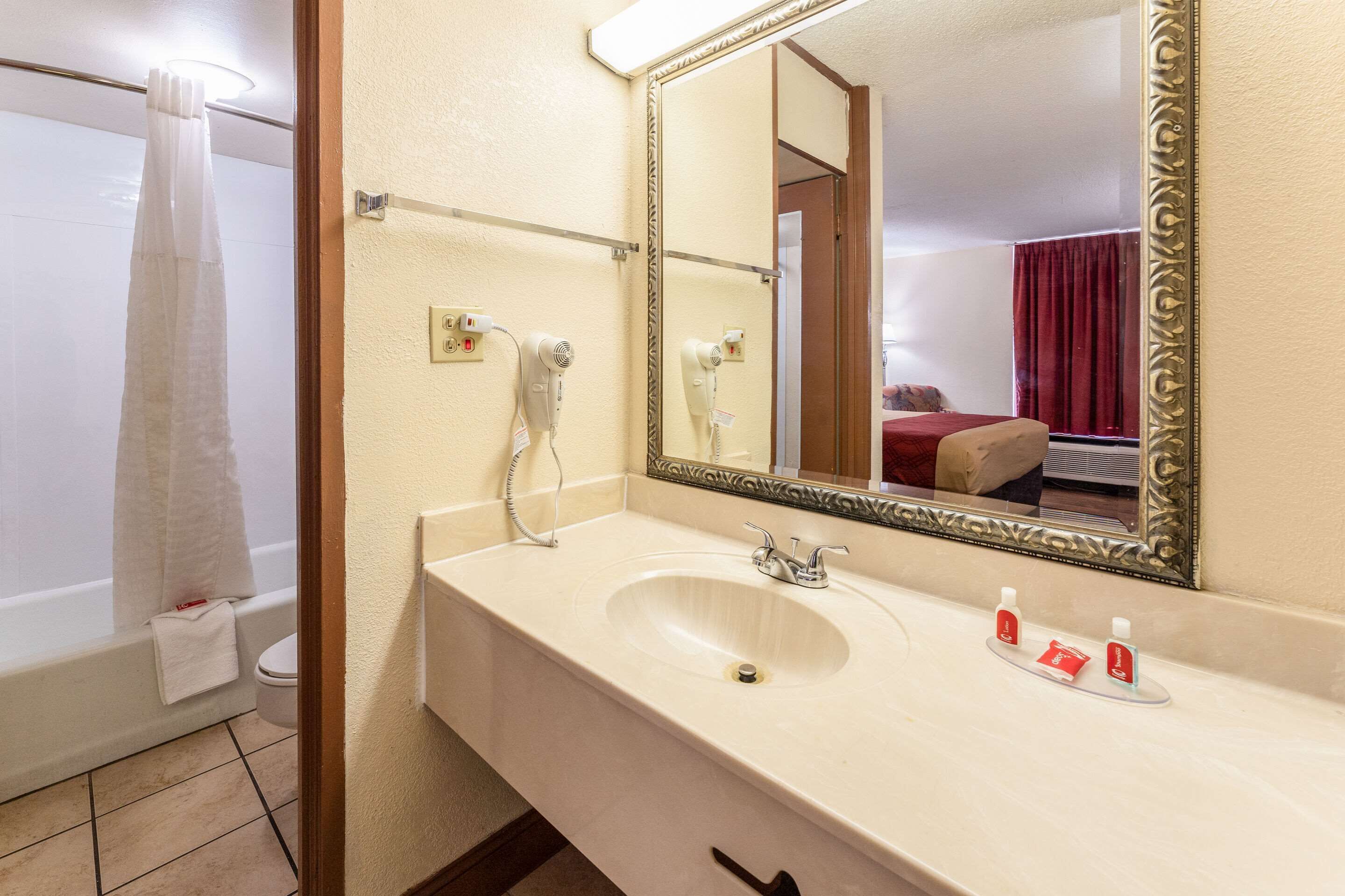Ein Badezimmer mit Waschbecken, Spiegel und zwei Haartrocknern an der Wand.