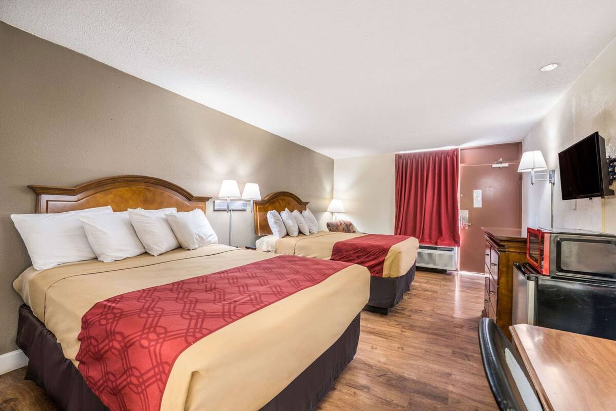 Une chambre d’hôtel avec deux lits, une télévision, un four à micro-ondes et un rideau rouge.
