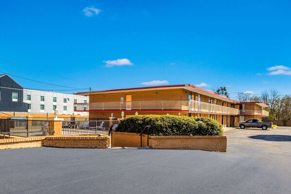 A two-story motel with a red roof, a parking lot, and a small garden area. - Econo Lodge  Inn & Suites Macon West (Macon)