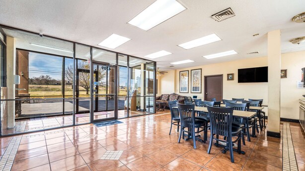 A spacious room with large windows, a flat-screen TV, and a dining area with tables and chairs. - Econo Lodge  Inn & Suites Macon West (Macon)