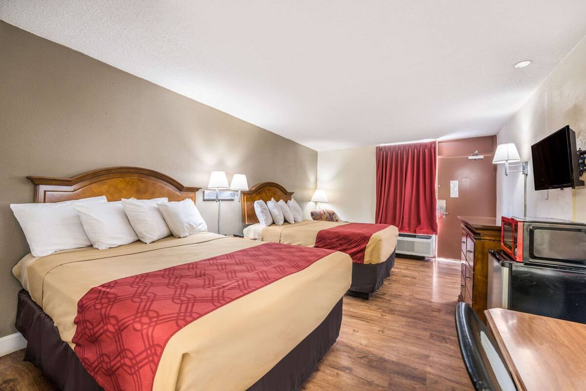 Une chambre d’hôtel avec deux lits, une télévision, un four à micro-ondes et une petite kitchenette.