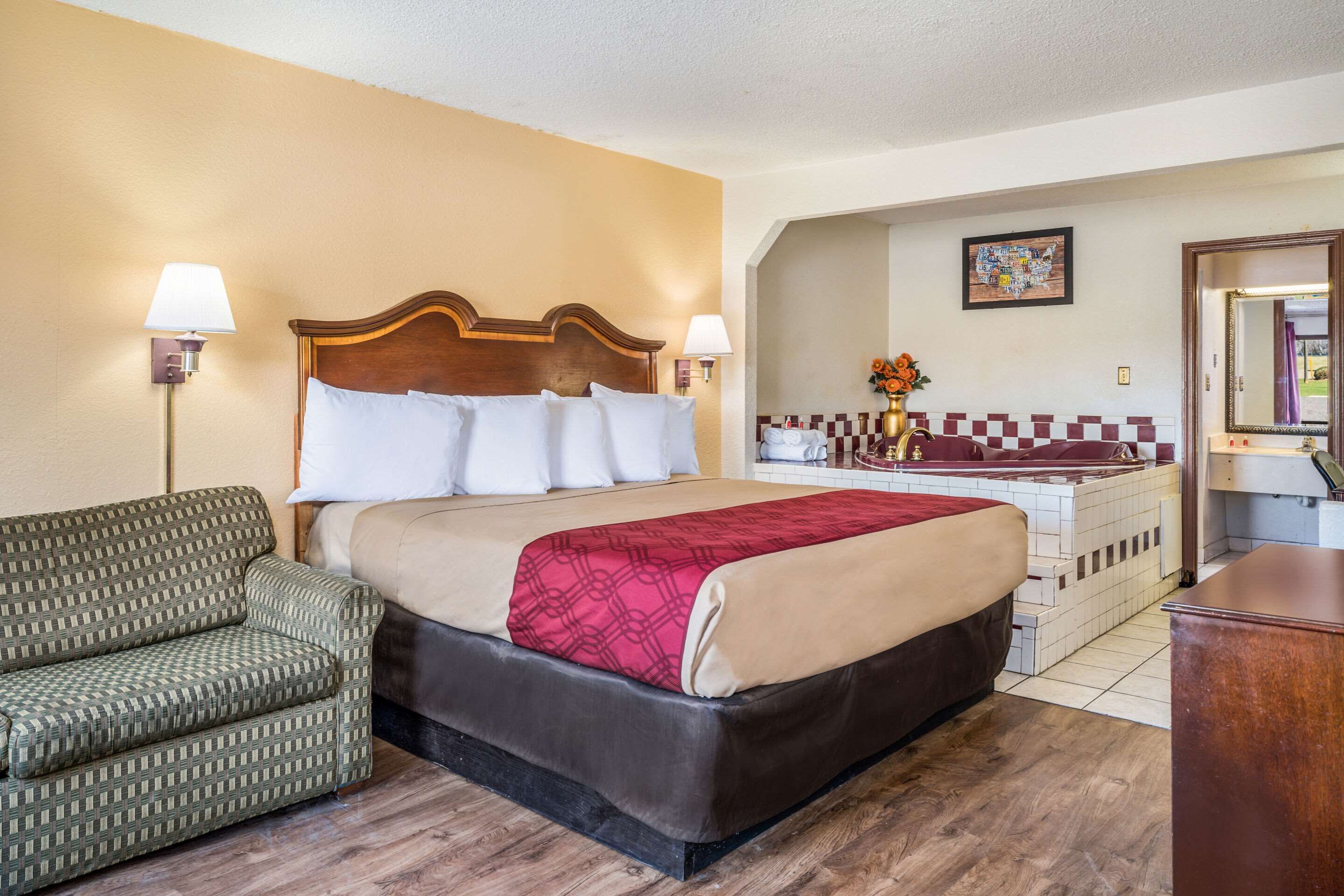 A hotel room with a bed, a sofa, a bathroom with a bathtub, and a small desk.