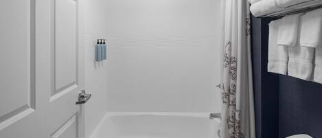 A bathroom with a bathtub, a shower curtain, and a towel rack with towels.