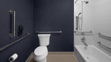 A modern bathroom with a white toilet, a shower area with grab bars, and a towel rack.