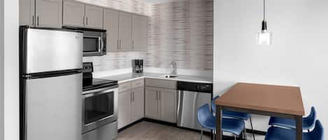 A modern kitchen with stainless steel appliances, a wooden dining table, and blue chairs.