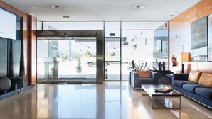 Un hall d’entrée moderne avec une porte d’entrée en verre, un canapé, une table basse et un grand tableau abstrait accroché au mur.
