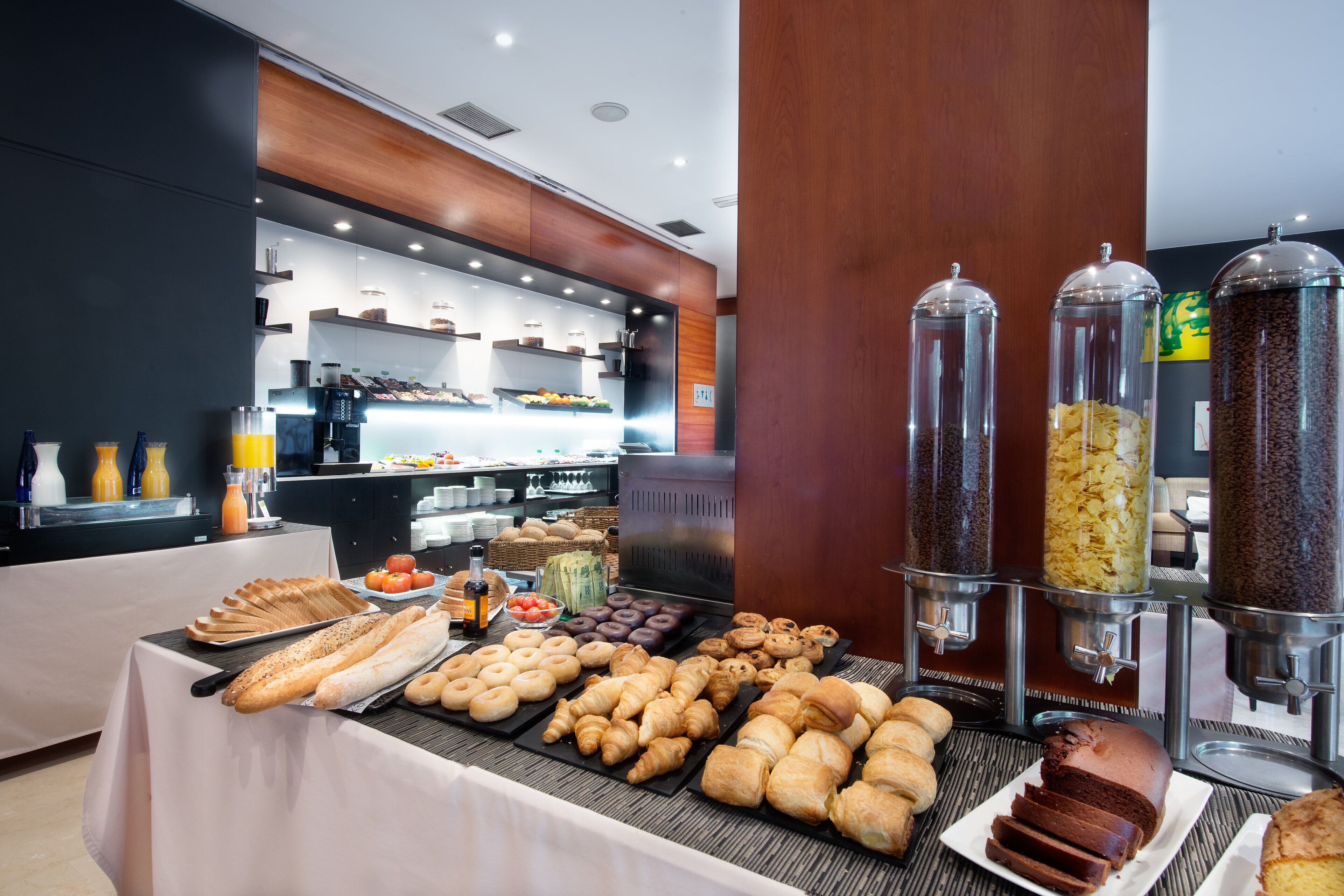 A buffet with various baked goods and pastries, including bread, croissants, and a chocolate cake.