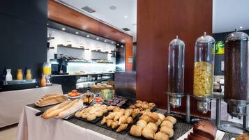 A buffet with various baked goods and pastries, including bread, croissants, and a chocolate cake.