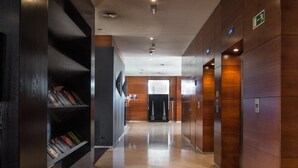 Un couloir moderne avec un lambris en bois, un plancher poli et un espace d’accueil doté d’un comptoir et de chaises.