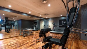 Une salle de sport équipée de matériel d’exercice, dotée d’un plancher en bois et de murs recouverts de miroirs.
