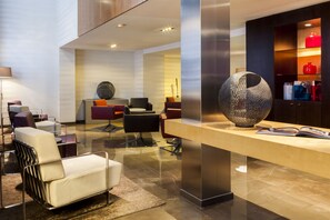 A modern reception area with a reception desk, seating area, and a decorative spherical sculpture. - AC Hotel Irla by Marriott (Barcelona)