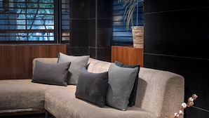 A modern living room with a sectional sofa, a wooden side table, and a vase with dried flowers. - AC Hotel Irla by Marriott (Barcelona)
