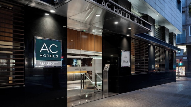 A modern hotel entrance with a glass facade, a visible reception desk, and a sign indicating it is part of the AC Hotels Marriott chain. - AC Hotel Irla by Marriott (Barcelona)