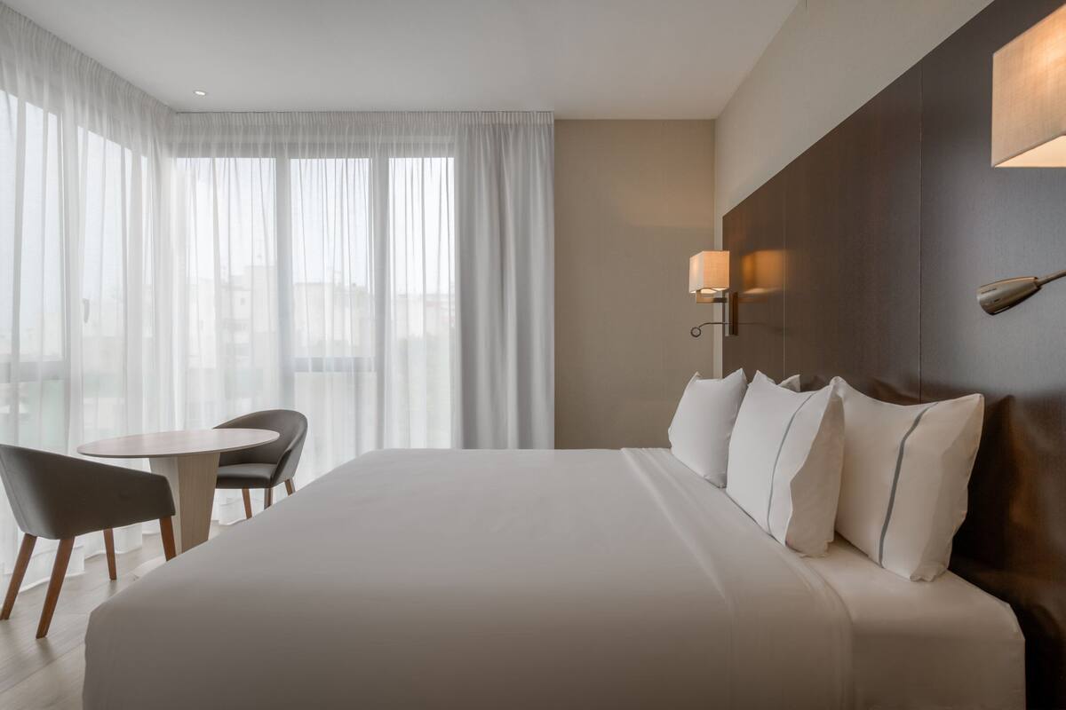 Een hotelkamer met een groot bed, een ronde tafel en twee stoelen.